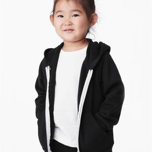 a little girl wearing a black and white hoodie