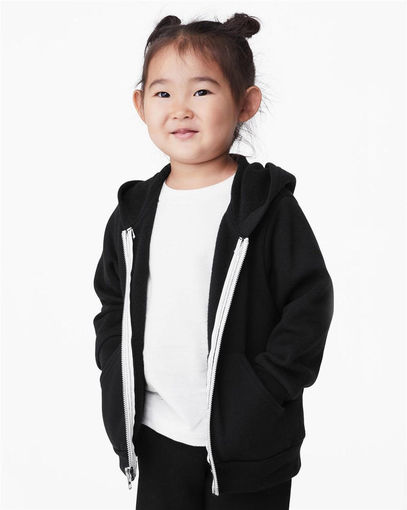 a little girl wearing a black and white hoodie