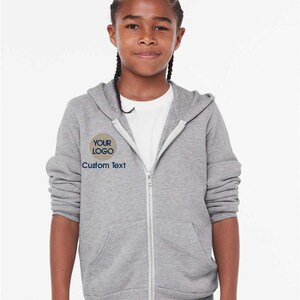 a young girl wearing a gray sweatshirt and shorts