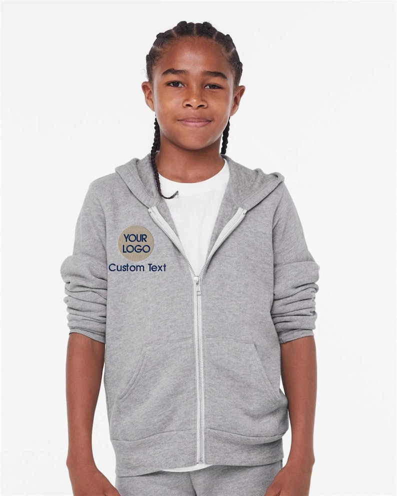 a young girl wearing a gray sweatshirt and shorts