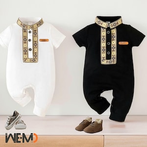 May include: Two baby onesies with short sleeves and a button closure. One onesie is white with gold trim and the other is black with gold trim. Both onesies have a small name tag on the front. The onesies are on a white background.