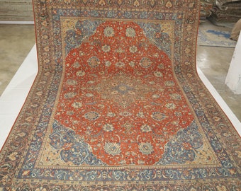 May include: A large, intricately patterned rug with a red center and blue and beige borders. The rug has a traditional Persian design with floral motifs and geometric shapes.
