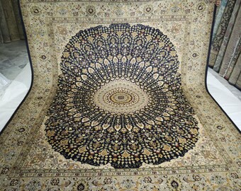 May include: An ornate, large area rug with a central medallion design. The rug features a dark navy blue center with a detailed, symmetrical pattern in gold and cream colors. The border is a lighter cream color with intricate floral motifs.