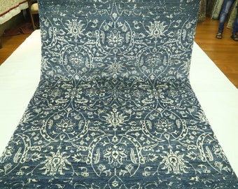 Puede incluir: Una alfombra azul y blanca con un diseño floral. La alfombra está doblada por la mitad y está sobre una superficie blanca.