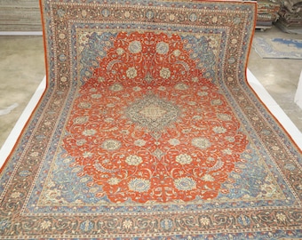 May include: A large, intricately patterned rug with a red center and blue and brown borders. The rug has a floral design and is made of wool.