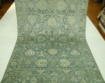 Puede incluir: Una alfombra azul claro con un patrón floral tradicional en un tono beige más claro. La alfombra tiene un brillo sutil y una textura suave.