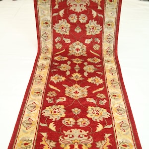 Könnte beinhalten: Ein roter Läufer mit einem floralen Muster in Creme und Gold. Der Läufer hat einen cremefarbenen Rand mit einem sich wiederholenden Muster.