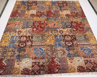 May include: A colorful patchwork rug with a variety of intricate patterns in shades of red, blue, gold, and cream. The rug has a fringed edge.