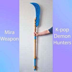 May include: A blue and gold Mira weapon with a curved blade and intricate designs. The weapon has a long, wooden-colored shaft with blue and gold accents. Text on the image reads "Mira Weapon" and "K-pop Demon Hunters".