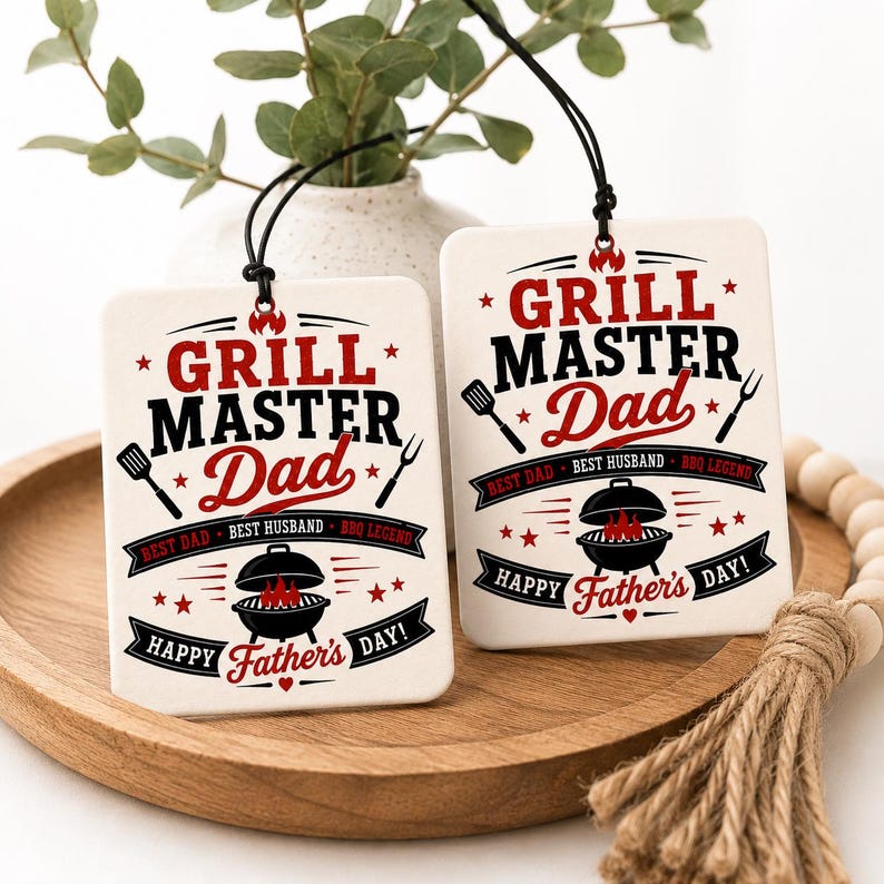 K&ouml;nnte beinhalten: Zwei rechteckige, wei&szlig;e H&auml;ngeschmuckst&uuml;cke mit schwarzen und roten Grafikdesigns. Der Text lautet Grill Master Dad, Best Dad, Best Husband, BBQ Legend und Happy Father's Day, erg&auml;nzt durch Abbildungen eines Grills, eines Wenders und einer Gabel.