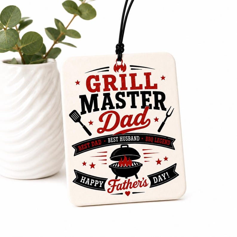 K&ouml;nnte beinhalten: Ein rechteckiges wei&szlig;es H&auml;ngeschild mit schwarzer Kordel und rotem sowie schwarzem Text, der GRILL MASTER Dad, BEST DAD, BEST HUSBAND, BBQ LEGEND und HAPPY Father's DAY! lautet. Das Design enth&auml;lt Abbildungen eines Pfannenwenders, einer Gabel und eines Grills.