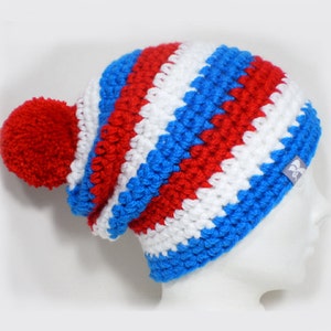 Puede incluir: Un gorro de punto de rayas rojas, blancas y azules con un pompón rojo en la parte superior.