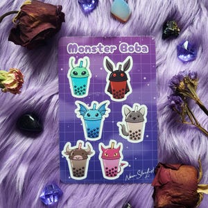 Può includere: Un foglio di adesivi con il testo "Monster Boba" con sei disegni di tè boba a cartoni animati con personaggi a tema mostruoso. Gli adesivi sono su uno sfondo a griglia viola, circondati da finta pelliccia viola, cristalli e fiori secchi.