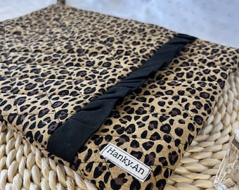 May include: A brown and black leopard print quilted clutch with a black fabric flap and the text "Hanky.An" on the front.