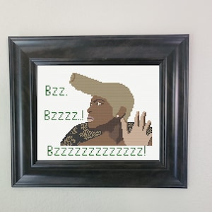 Può includere: Opera d'arte a punto croce incorniciata raffigurante una donna con una grande acconciatura, mano alzata in gesto di stop. Il testo recita "Bzz. Bzzzz.! Bzzzzzzzzzzzzzz!" in verde. La cornice è nera.