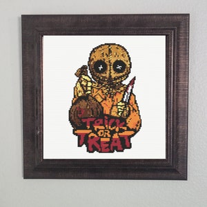 May include: A cross-stitch pattern featuring a pixelated illustration of a scary, grinning character holding a knife and a bag of candy. The text "Trick or Treat" is below the character.