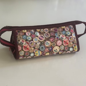 May include: A brown zippered pouch with pink zipper pulls and a fabric design of colorful spools of thread.