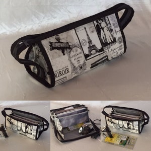 May include: A black and white fabric zippered pouch with a Parisian theme. The pouch is open to reveal multiple compartments and a black and silver iron.