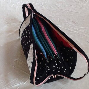 May include: A black and white polka dot zippered pouch with a pink zipper. The pouch is open and filled with colorful fabric scraps.