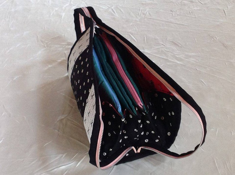 May include: A black and white polka dot zippered pouch with a pink zipper. The pouch is open and filled with colorful fabric scraps.