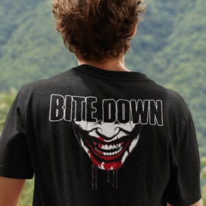 Può includere: Maglietta nera con una grafica bianca di una bocca sorridente e sanguinante con il testo "BITE DOWN" sopra.