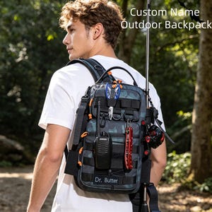 Può includere: Uno zaino tattico mimetico grigio scuro con il testo Custom Name Outdoor Backpack e una targhetta con il nome Dr. Butter. Lo zaino presenta cinghie multiple, anelli a D, un walkie-talkie nero, un multiuso rosso e delle pinze blu.