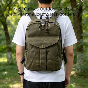 Könnte beinhalten: Ein olivgrüner Outdoor-Rucksack aus gewachstem Canvas mit einer Vordertasche mit Messing-Druckknopf, einem Tragegriff, verstellbaren Schultergurten und einem personalisierten Wasserflaschen-Clip. Der Text lautet: Waxed Canvas Outdoor Backpack with Personalized Water-Bottle Clip.