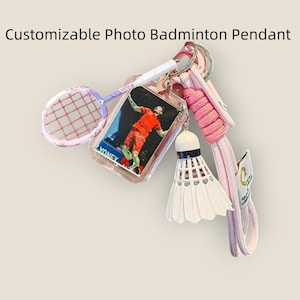 Könnte beinhalten: Ein personalisierbarer Badminton-Schlüsselanhänger mit einem Miniatur-Badmintonschläger, einem Federball und einem Foto eines Badmintonspielers. Der Anhänger ist an einem rosa Schlüsselband befestigt. Der Text "Customizable Photo Badminton Pendant" steht oben.