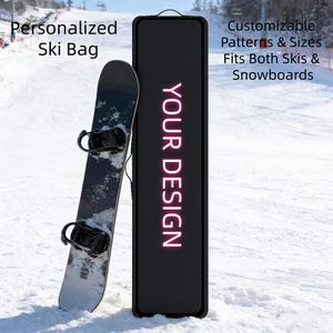 May include: A black ski bag with the text "YOUR DESIGN" in pink neon, leaning against a snowboard on a snowy slope. The bag is designed to fit both skis and snowboards, with customizable patterns and sizes. The words "Personalized Ski Bag" are visible.