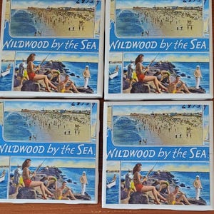 May include: Four square ceramic coasters with a vintage postcard design featuring a beach scene with people and the text "WILDWOOD by the SEA".