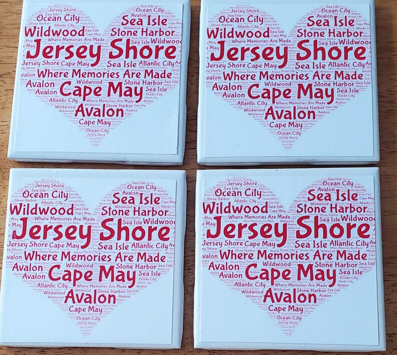 K&ouml;nnte beinhalten: Vier wei&szlig;e Keramikuntersetzer mit herzf&ouml;rmigem Design. Das Design zeigt die W&ouml;rter "Jersey Shore", "Cape May" und andere K&uuml;stenstadtnamen in roter Schrift, wodurch ein Collage-Effekt entsteht.