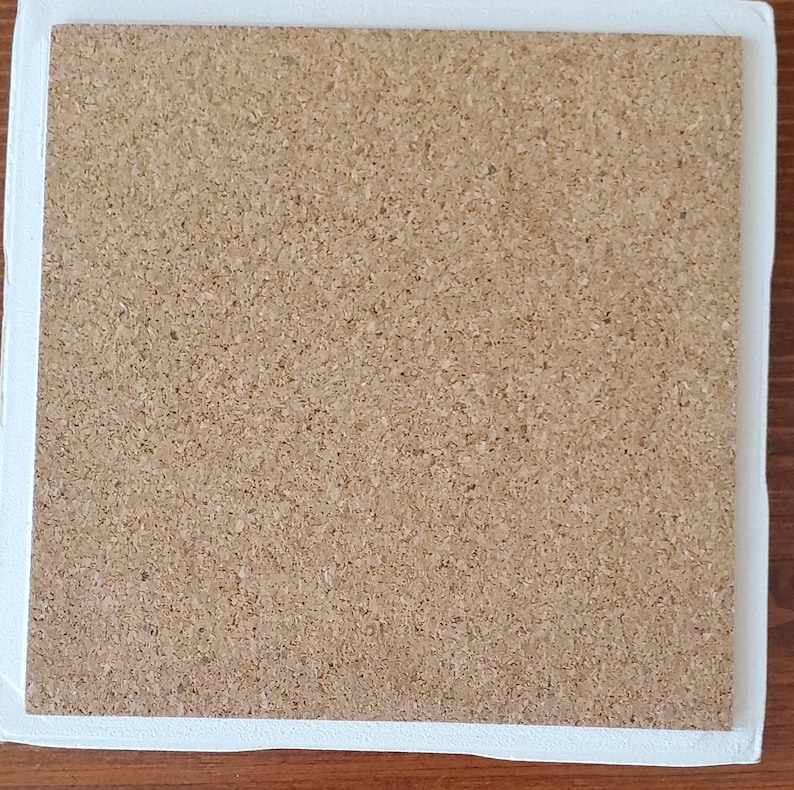K&ouml;nnte beinhalten: Quadratischer Korkuntersetzer mit wei&szlig;em Rand. Der Untersetzer hat eine hellbraune, strukturierte Oberfl&auml;che und einen wei&szlig;en Rand. Der Untersetzer dient wahrscheinlich zum Schutz von Oberfl&auml;chen.