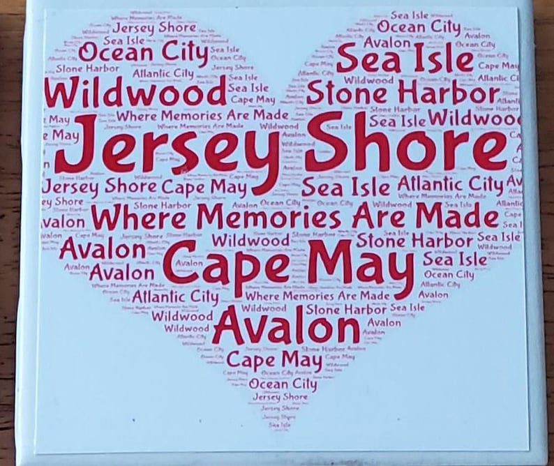 K&ouml;nnte beinhalten: Eine quadratische wei&szlig;e Kachel mit einem herzf&ouml;rmigen Design, das mit rotem Text gef&uuml;llt ist. Der Text enth&auml;lt die W&ouml;rter "Jersey Shore", "Cape May" und andere K&uuml;stenst&auml;dte. Der Satz "Where Memories Are Made" ist ebenfalls enthalten.