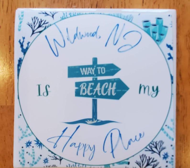 May include: White ceramic coaster with a blue and white design. The coaster features a sign that says "Way to Beach" and the text "Wildwood, NJ is my happy place".