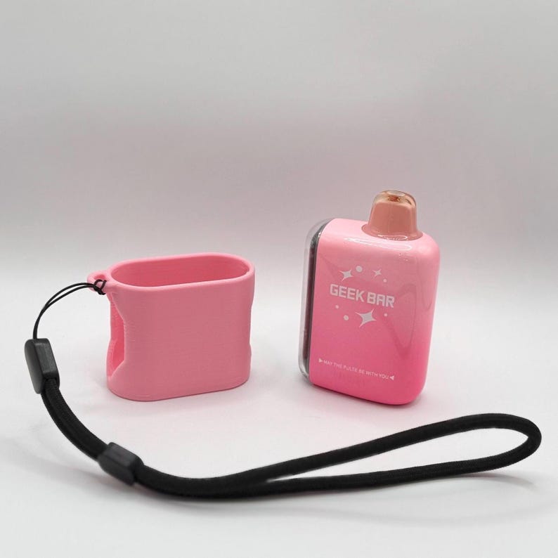 Op de afbeelding: Een roze Geek Bar wegwerp-vape-apparaat met een bijpassende roze siliconen beschermhoes en een zwart koord. Het apparaat heeft een roze verloopafwerking, een doorschijnend mondstuk en de tekst GEEK BAR op de voorzijde gedrukt.