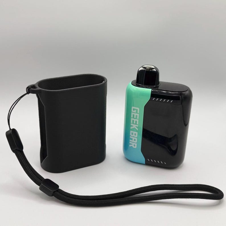 Op de afbeelding: Een zwarte siliconen beschermhoes met een bevestigd zwart koord naast een Geek Bar wegwerp-vape-apparaat. De vape heeft een glanzende zwarte en blauwgroene gradi&euml;ntafwerking met de tekst GEEK BAR verticaal in het wit gedrukt.