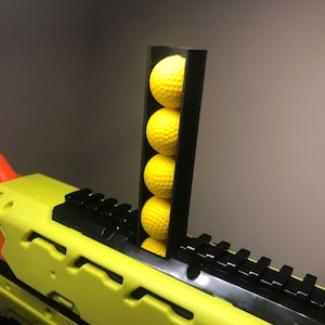May include: A black plastic magazine extension for a Nerf gun, holding five yellow foam darts.