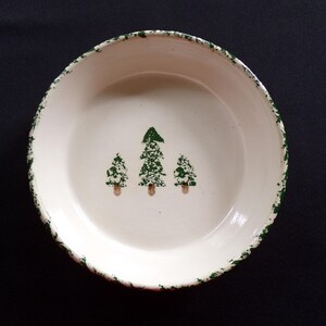 May include: White ceramic pie plate with a green rim and three green trees painted on the bottom.
