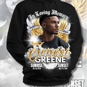 May include: Black hoodie with a graphic design featuring a portrait, angel wings, doves, and the text "In Loving Memory." The name "Ernest Greene" is displayed with sunrise and sunset dates.