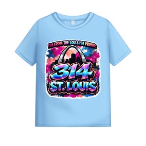May include: Light blue t-shirt featuring a colorful graphic design. The design includes the text "I'M FROM THE LOU & I'M PROUD" above the number "314" and the words "ST. LOUIS". The graphic also features an arch and a cityscape.