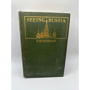 May include: A green hardcover book titled Seeing Russia by E.M. Newman. The front cover features a gold-colored illustration of a cathedral with onion domes enclosed within a rectangular border, with the title and author name in gold lettering.