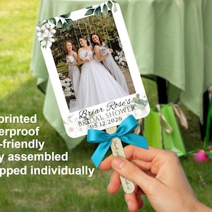 Puede incluir: Un abanico de boda personalizado con una foto de una novia y sus damas de honor. El abanico presenta detalles florales, una cinta color turquesa y el texto "Briar Rose's Bridal Shower 05.12.2026".