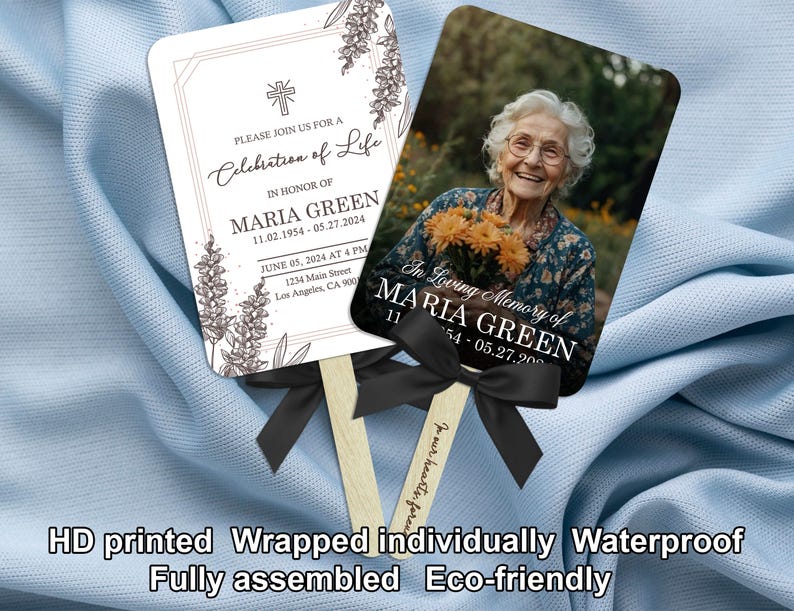 Puede incluir: Dos abanicos conmemorativos con mangos de madera y lazos negros. Un abanico presenta una foto de una anciana sosteniendo flores, con el texto "In Loving Memory of Maria Green". El otro abanico tiene el texto "Please join us for a Celebration of Life."