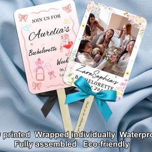 May include: Two personalized bachelorette party fans. One pink fan features text "Join us for Aurelia's Bachelorette Week". The other fan has a photo and text "Zara Sophia's Bachelorette". Both fans have wooden sticks and are decorated with bows.