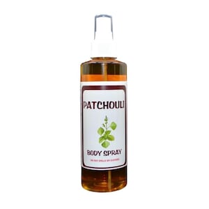 Puede incluir: Un frasco rociador de vidrio transparente lleno de un líquido marrón dorado. La etiqueta dice "Patchouli Body Spray" con una ilustración de una planta verde. El frasco tiene una boquilla rociadora blanca y una tapa marrón. El texto "Do not spray on clothes" también está en la etiqueta.