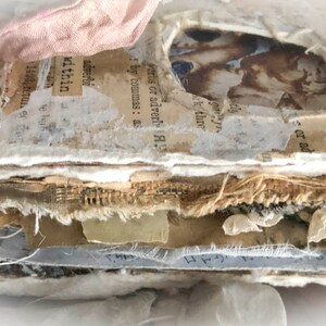 May include: A stack of paper and fabric pages with a vintage feel. The pages are layered and distressed, with visible text and images. The top page has the text "FREEDOM - THE HOD" and "ing rule".