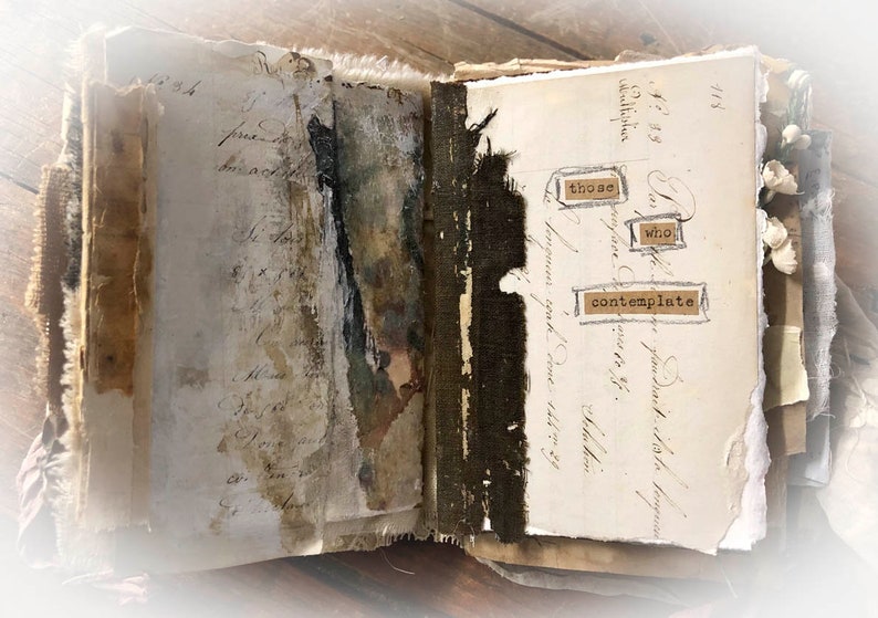 May include: An open journal with pages of old, handwritten text and a dark brown fabric spine. The pages are decorated with brown paper scraps and a few words are cut out and pasted on the page: "those who contemplate".