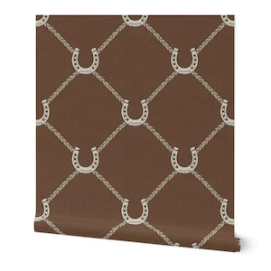May include: Brown wallpaper roll featuring a repeating pattern of white horseshoes connected by beige rope. The horseshoes are outlined in a darker color, creating a textured effect. The background is a solid, warm brown.