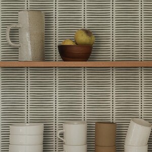 May include: A collection of ceramic kitchenware including a speckled pitcher, a dark wooden bowl with two yellow fruits, a stack of four white bowls, two white mugs, two brown cylindrical cups, and two white speckled cups on wooden shelves.