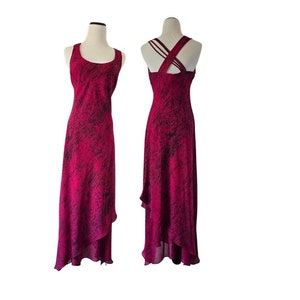 May include: A sleeveless, floor-length dress in a vibrant fuchsia hue with a dark, textured pattern. The dress features a scoop neckline and a flowing, asymmetrical hemline. The back of the dress has a crisscross strap design.